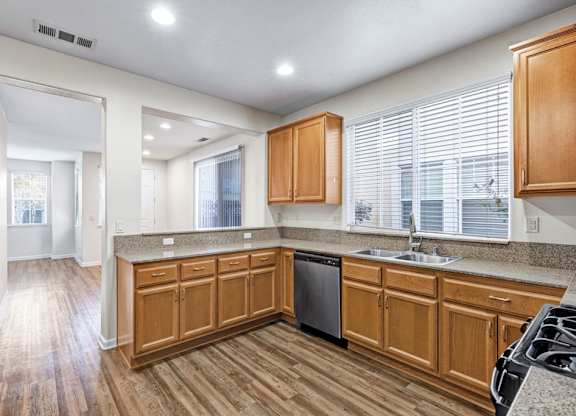 A kitchen with wooden cabinets and a black dishwasher.