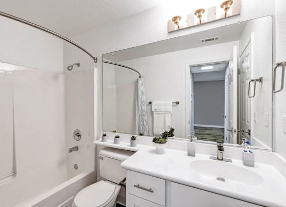 A white bathroom with a toilet, sink, and mirror.