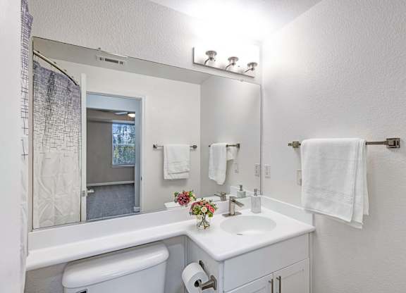 A white bathroom with a toilet, sink, and mirror.