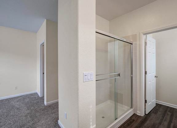 A room with a glass shower stall and a white door.