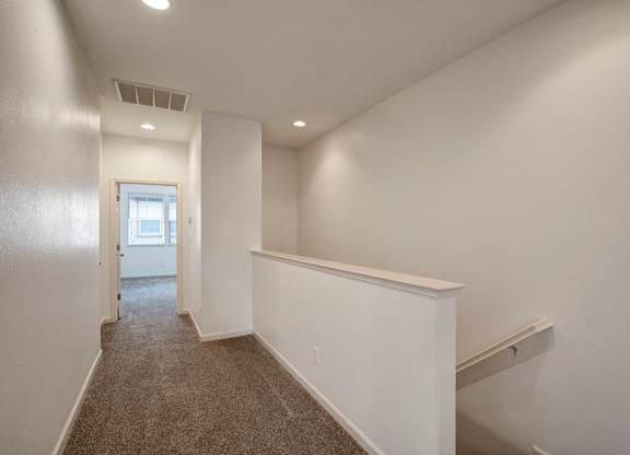 A long hallway with a carpeted floor and white walls.