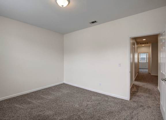 A room with a carpeted floor and a doorway leading to another room.