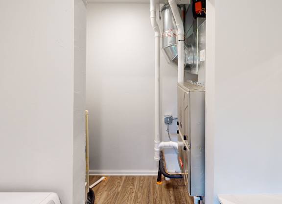 A white wall with a pipe and a white chair.