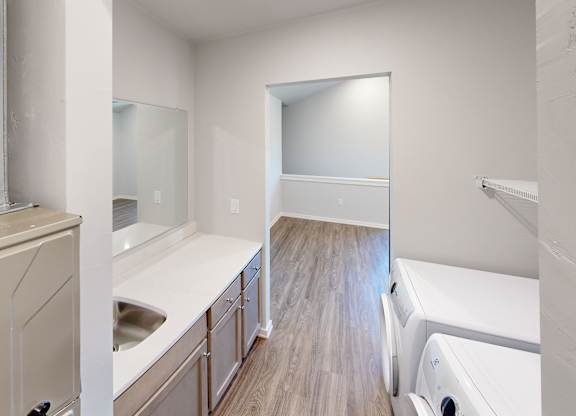 A kitchen with white appliances and wooden floors.