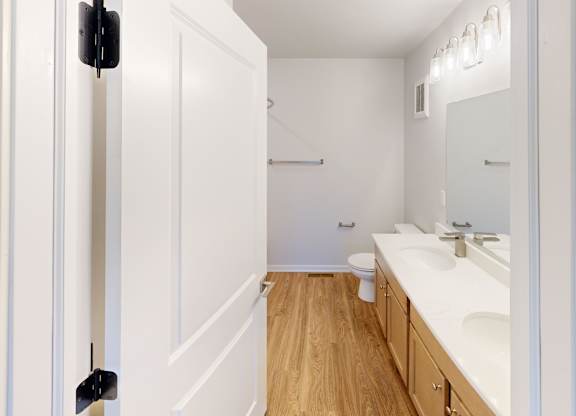 A white bathroom with a toilet, sink, and mirror.