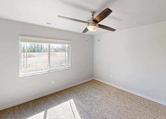 A room with a ceiling fan and carpeted floor.