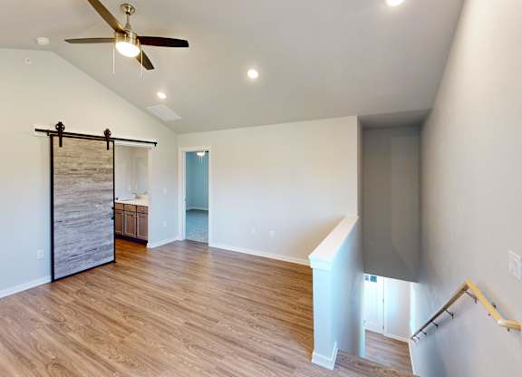 A room with a ceiling fan and wooden flooring.