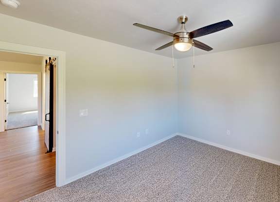 A room with a ceiling fan and carpeted floor.