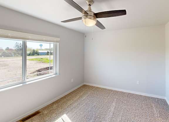 A room with a ceiling fan and a carpeted floor.