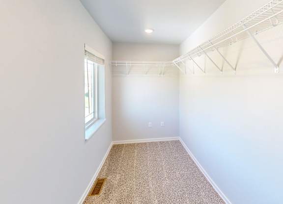 A room with white walls and a window on the left side.