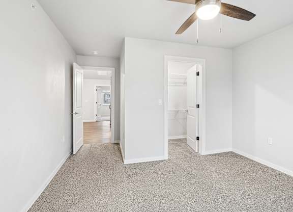 A room with a ceiling fan and carpeted floor.