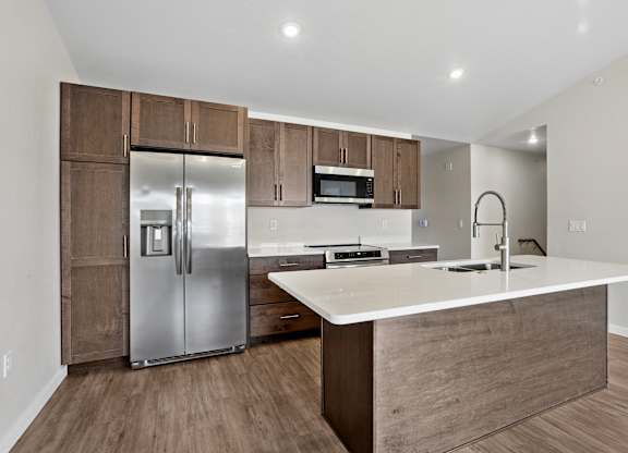 A modern kitchen with a refrigerator, microwave, and oven.