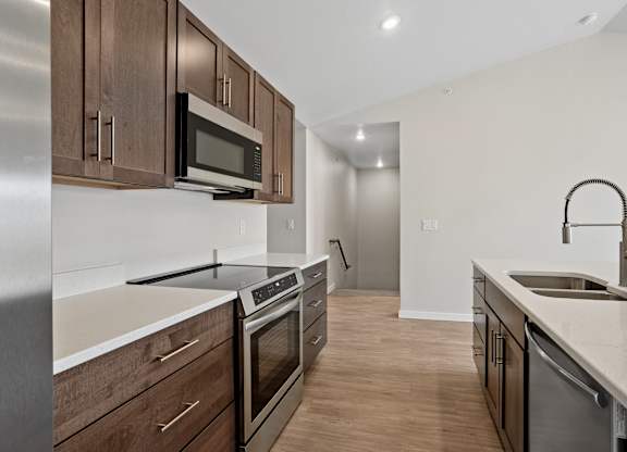 A modern kitchen with dark wood cabinets and stainless steel appliances.