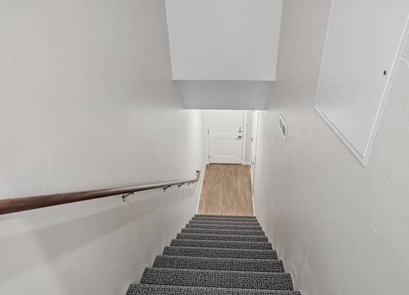 A stairway with a wooden floor and a metal handrail.