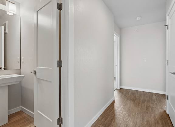 A white bathroom with a wooden floor and a white door.