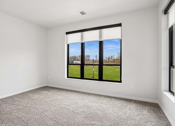 A room with a large window overlooking a grassy field.