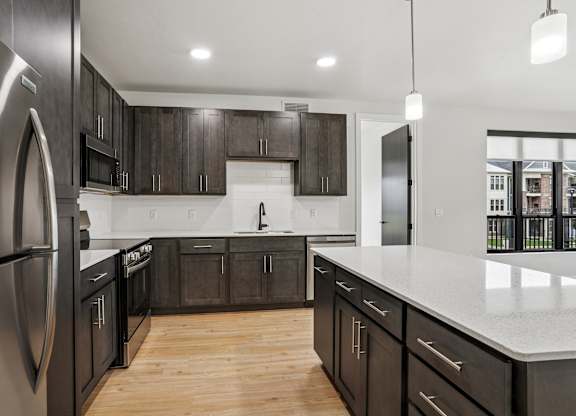 A modern kitchen with dark wood cabinets and stainless steel appliances.