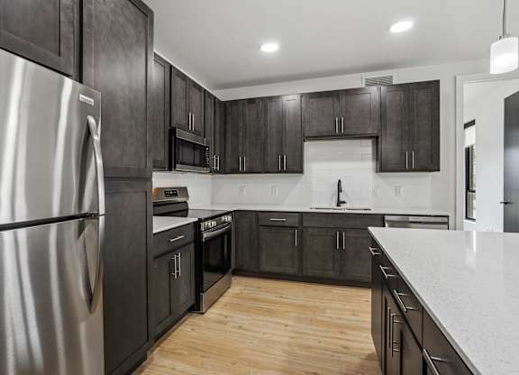 A modern kitchen with dark wood cabinets and a stainless steel refrigerator.