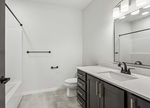 A bathroom with a toilet, sink, and mirror.