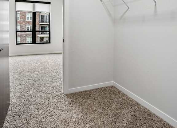A white room with a carpeted floor and a metal rack.