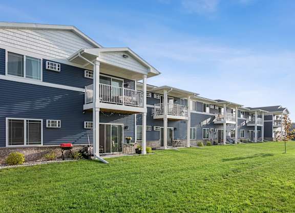 A row of houses with balconies and a green lawn in front.