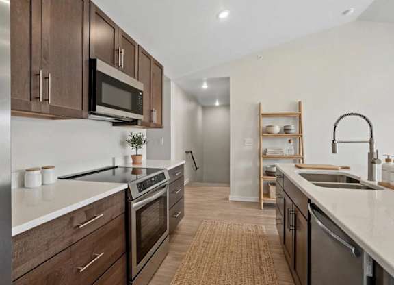 A modern kitchen with dark wood cabinets and stainless steel appliances.