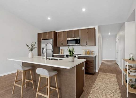 A kitchen with a white countertop and wooden bar stools.