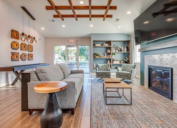 A modern living room with a grey couch, a wooden coffee table, and a fireplace.