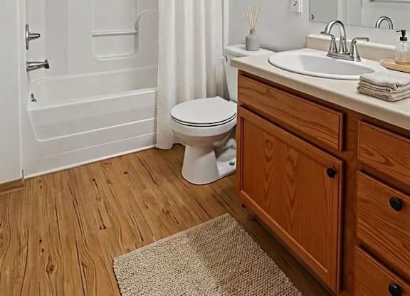 A white bathroom with wooden floors and a white toilet.