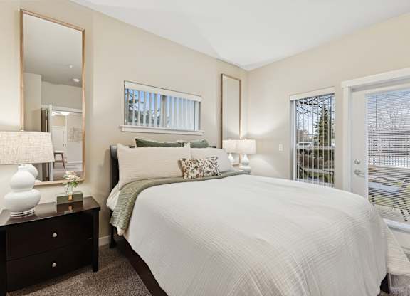 A bedroom with a large bed, a dresser with a mirror, and a window with blinds.