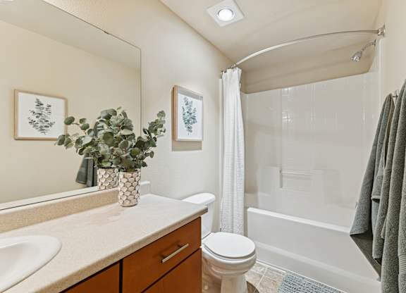 A bathroom with a white toilet, a white sink, a white bathtub, and a white shower curtain.