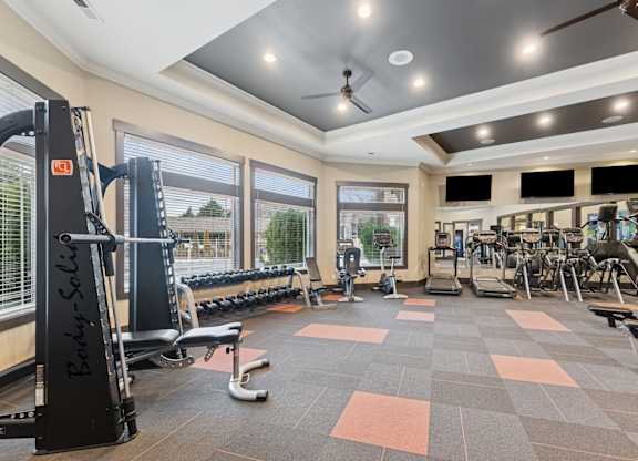 A gym with a variety of equipment including a weight bench, treadmill, and exercise machines.