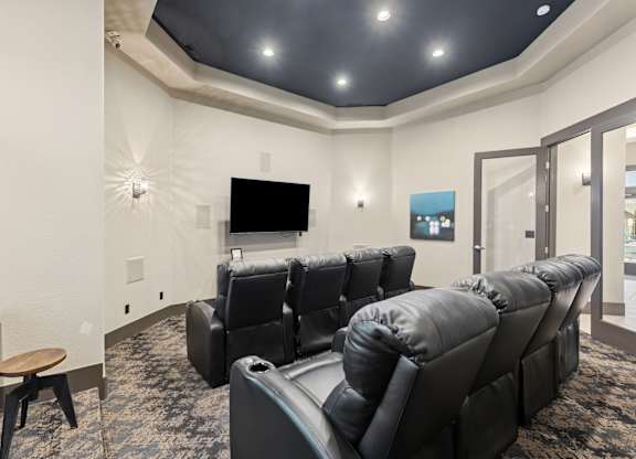 A row of black leather recliner chairs are lined up in a room.