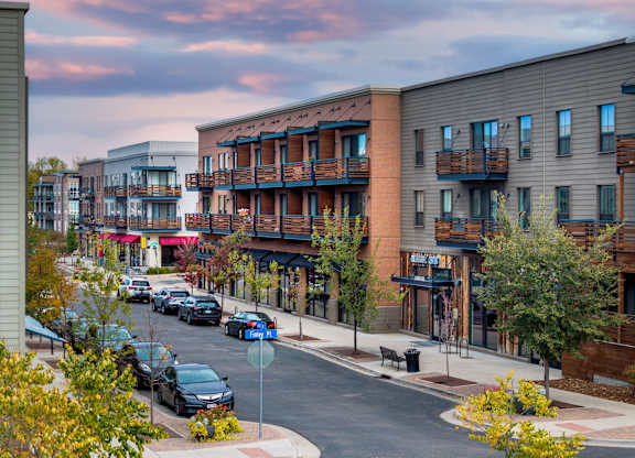A street view of a residential area with cars parked on the side of the road.
