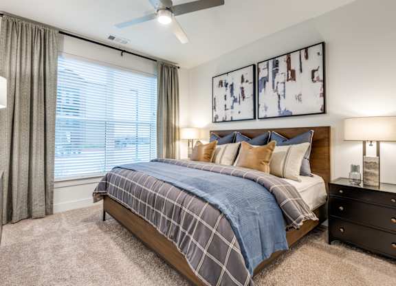 A bedroom with a bed, nightstands, and a ceiling fan.