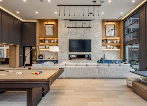 A modern living room with a pool table and a fireplace.