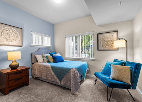 a bedroom with a bed and a chair and a window