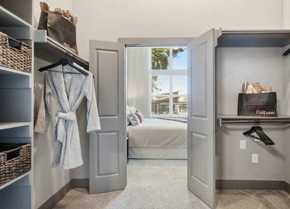 A bedroom with a bed and a closet with a grey robe hanging.