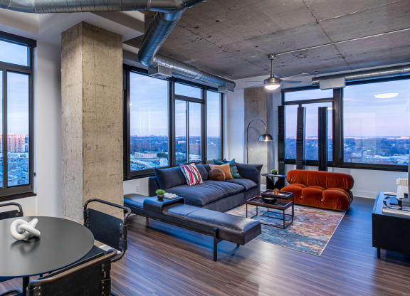 a living room with a couch and a table in a room with large windows