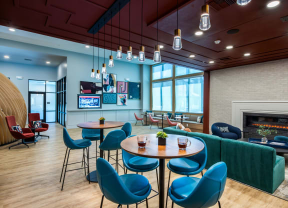 a lounge area with blue chairs and tables and a fireplace