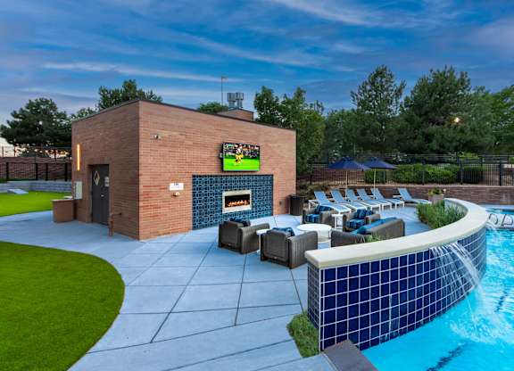 A modern outdoor pool area with a television and lounge chairs.