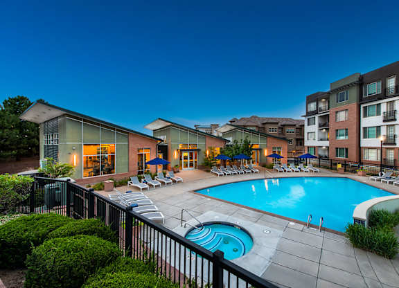 A swimming pool surrounded by a black fence and lounge chairs.