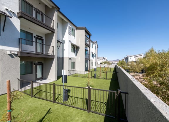 a view of an apartment complex with a green lawn and a fence
