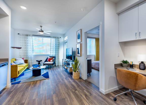 a living room with a couch and a desk and a window