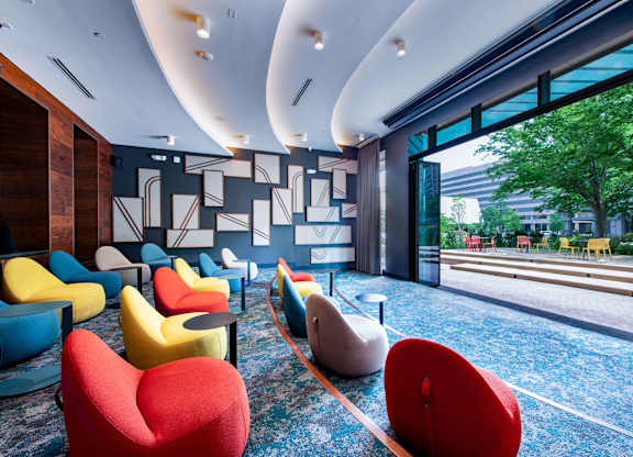 A room with a blue carpet and a row of colorful chairs.