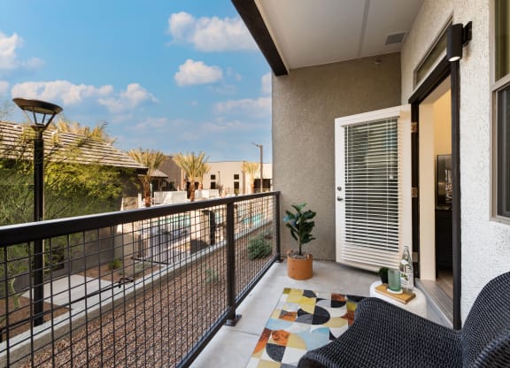 a balcony with a patio and two chairs and a potted plant