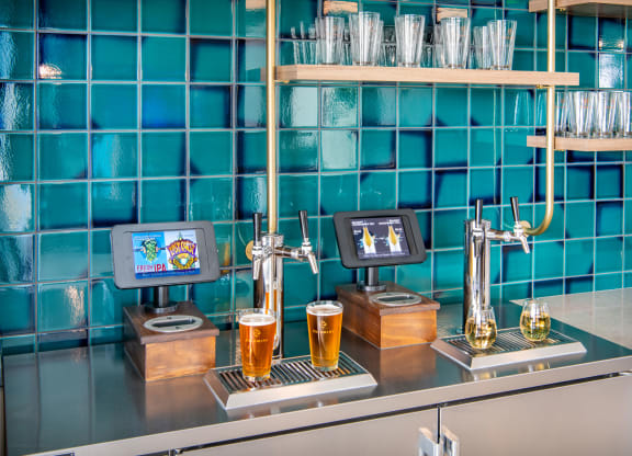 a bar with two pitchers of beer on a counter with blue tiles