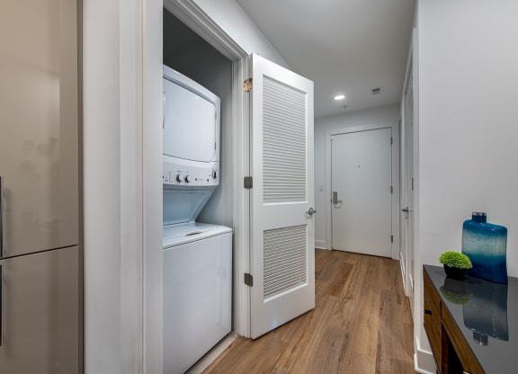 a small kitchen with a refrigerator and a washer and dryer in a closet