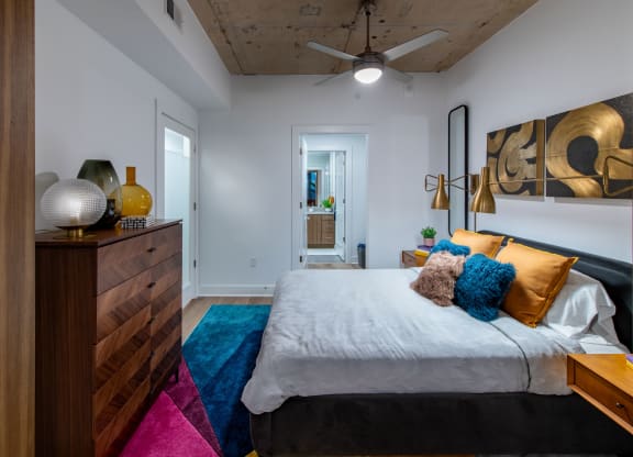 a bedroom with a bed and a dresser and a ceiling fan