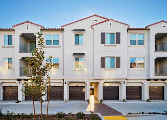 A row of townhouses with garages and balconies.